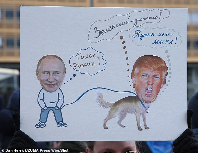 Un participante en una manifestación contra Vladimir Putin en Berlín tiene una señal con Putin sosteniendo a Trump con una correa