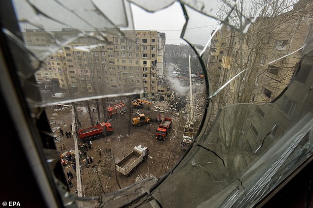 Una vista tomada a través del vaso roto de una ventana con vistas al sitio de un edificio residencial dañado a medida que las obras de rescate continúan, en Dnipro, sureste de Ucrania, el 15 de enero de 2023