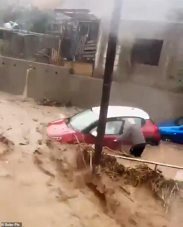 Un valiente transeúnte caminó a través del agua fangosa para liberar a la mujer de su auto antes de que pareciera hundirse casi