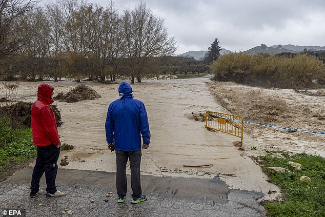 Los residentes miran un área inundada que bloquea un camino entre las ciudades de Cehegin y Canara el jueves después de que el río Argos se desbordó debido a fuertes lluvias en Murcia