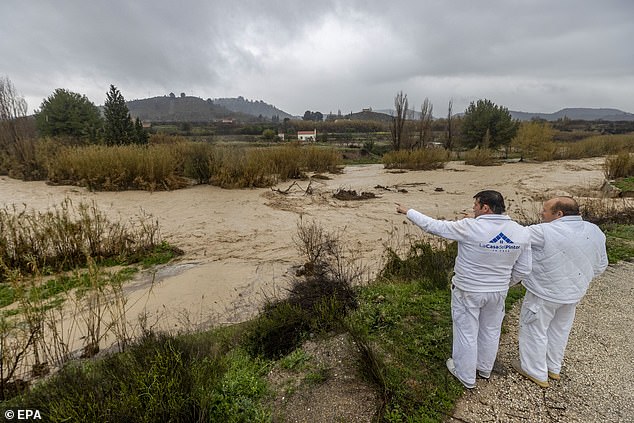 Dos hombres miran el río Argos en su camino a través de la ciudad de Cehegin después de fuertes lluvias en Murcia el jueves