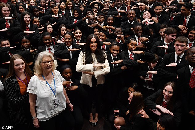 Meghan, duquesa de Sussex posa con niños en la escuela que hace el letrero de 'igualdad' después de una asamblea escolar durante una visita a la Escuela Robert Clack en Essex, el 6 de marzo de 2020, en apoyo del Día Internacional de la Mujer.