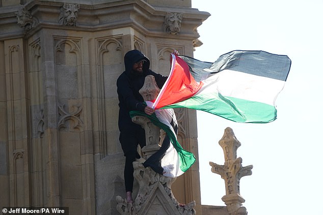 Un hombre agita la bandera palestina después de escalar la estructura de 96 metros de altura esta mañana