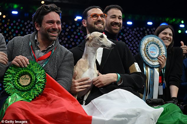 Miuccia, un whippet, posa con el propietario Giovanni Liguori, de Italia, y amigos y familiares después de ganar el título