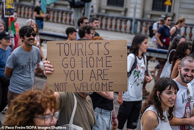 Portesters anti-turismo en España con un letrero que dice 'Los turistas se van a casa, no es bienvenido'